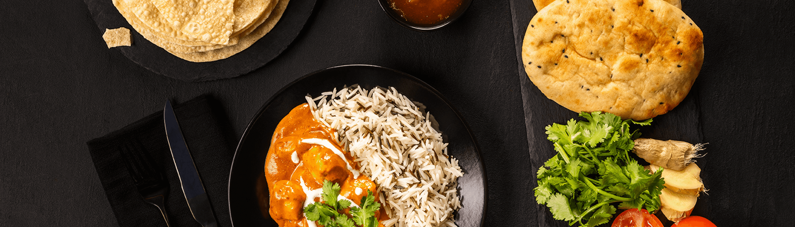 Image showing an Indian curry dish with naan bread and sides