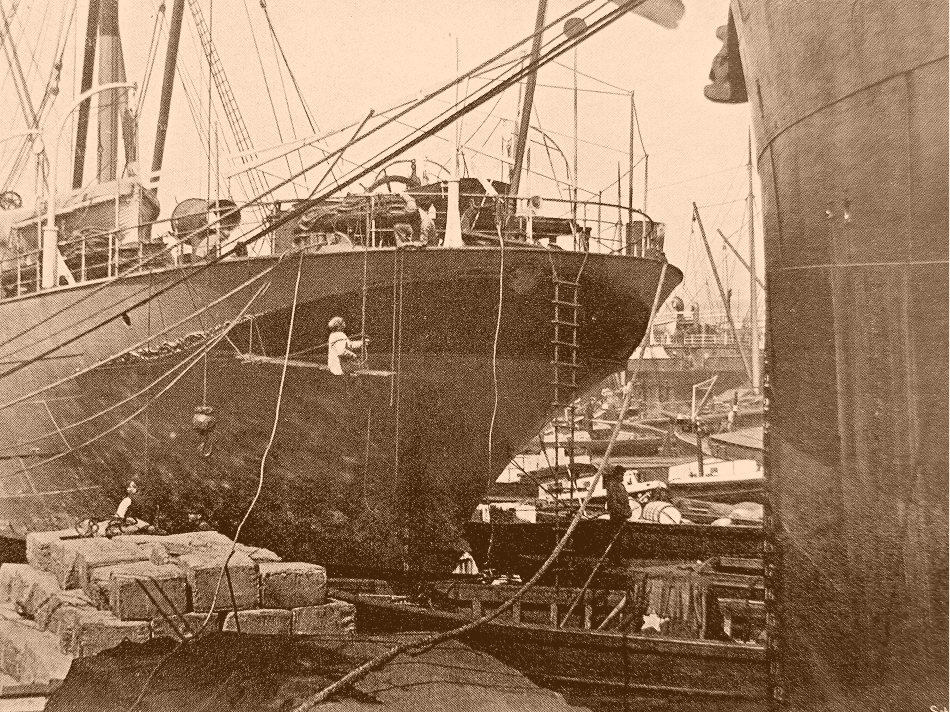 A historical image of a boat been loaded in a dockyard
